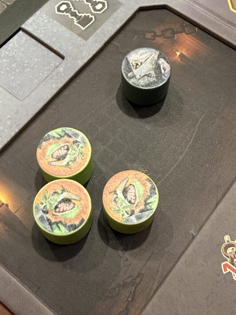 Jetons illustrés de Covenant photographiés à côté d’un élément du jeu.
